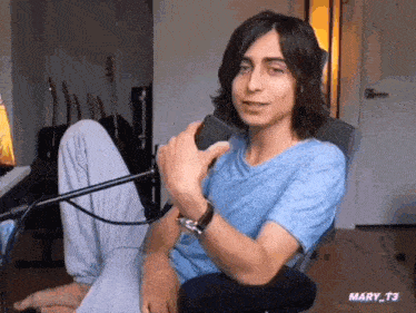 a man in a blue shirt is sitting in front of a microphone with the name mary t3 on the bottom right