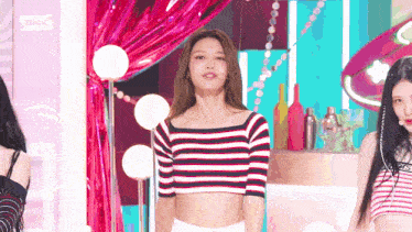 a woman in a striped crop top is standing on a stage with other women .