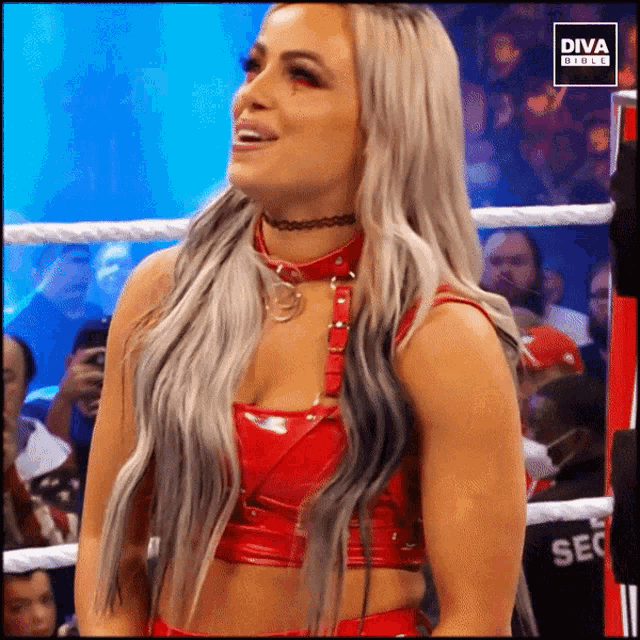 a woman in a red top and choker stands in a diva girls ring