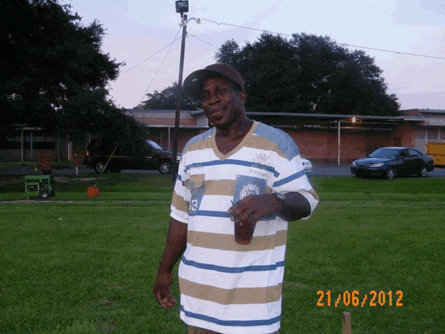 a man wearing a striped shirt with the number 13 on it stands in the grass