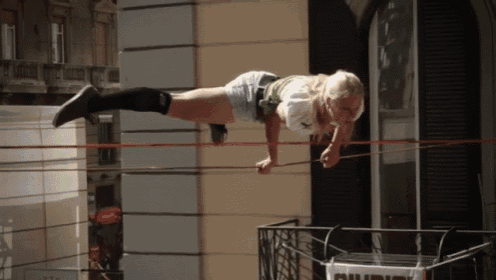 a woman is doing a handstand on a rope in front of a sign that says californs