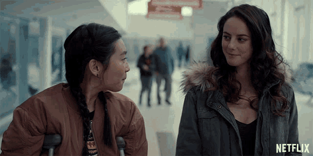 two women are standing next to each other in a hallway with a netflix logo in the corner