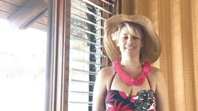 a woman wearing a straw hat and a lei is smiling .