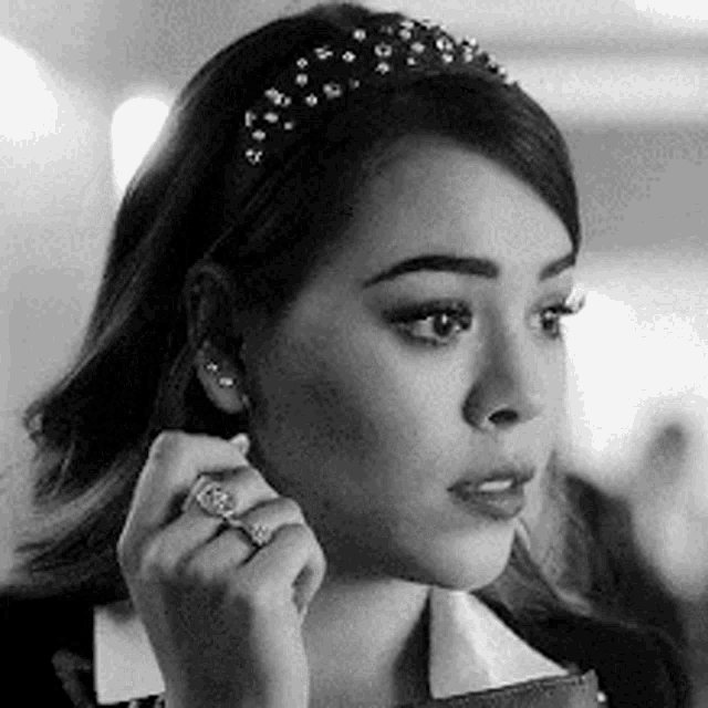 a black and white photo of a woman wearing a headband and ring .