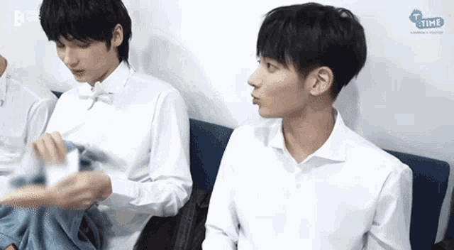 two young men are sitting next to each other on a blue couch .