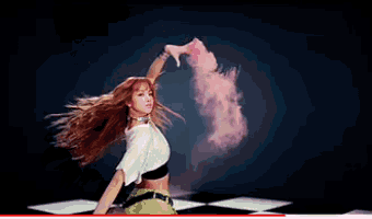 a woman is dancing on a checkered floor with pink smoke coming out of her hands .