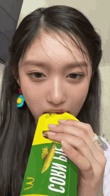 a woman is drinking from a carton that says " corn "