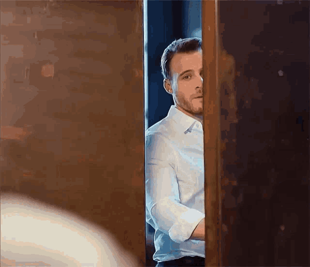 a man in a white shirt is standing in a doorway .