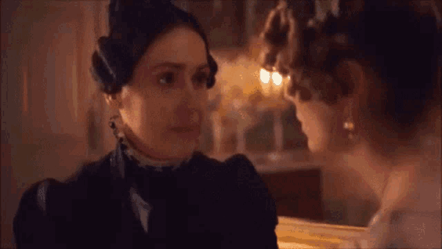 two women are standing next to each other and looking at each other in a room .