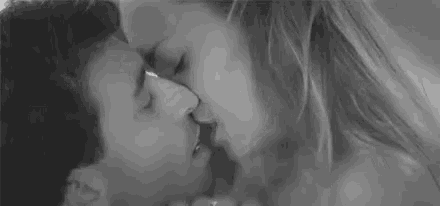 a black and white photo of a man and woman kissing each other .