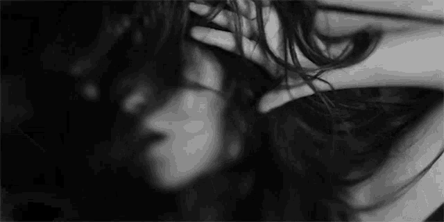 it is a black and white photo of a woman holding her hair .