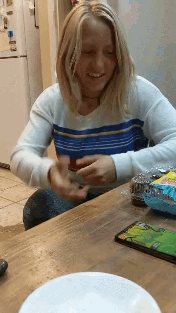 a woman is sitting at a table with a packet of candy in front of her