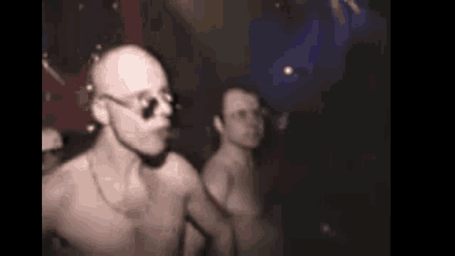 a group of men are dancing in a dark room without shirts .