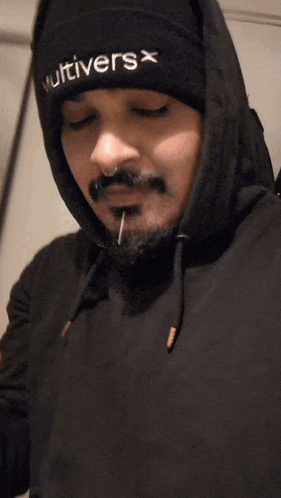 a man wearing a hoodie and a beanie has a needle in his nose .