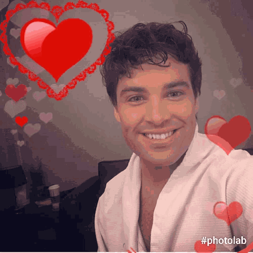 a man in a white shirt is smiling with a heart in the background