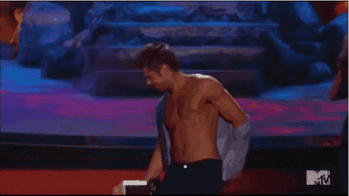 a shirtless man dancing on a stage with a mtv logo in the corner