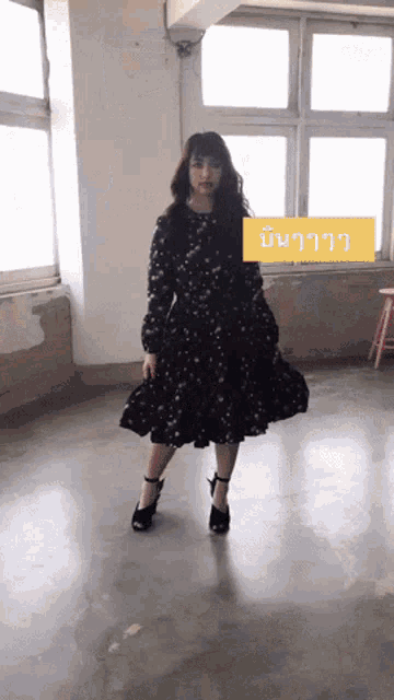 a woman in a black dress is standing in front of a window with a yellow sticker that says ' ll ' on it