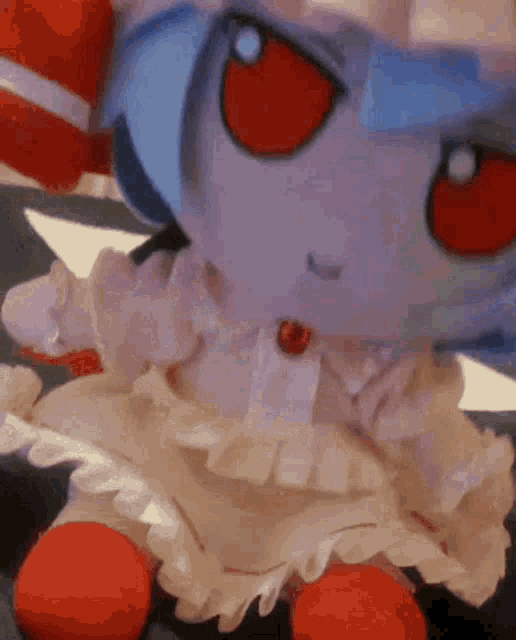 a stuffed doll with red eyes and blue hair is sitting on a table .