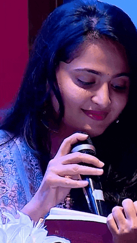 a close up of a woman holding a microphone and a book .