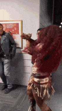 a woman with red hair is dancing in a room while a man stands behind her .