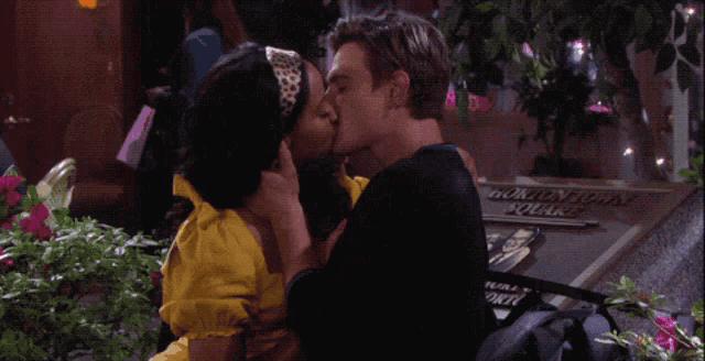 a man and a woman are kissing in front of a woman who is covering her mouth