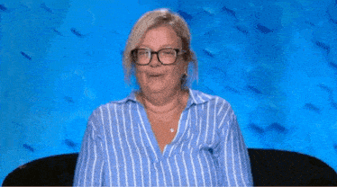 a woman wearing glasses and a blue and white striped shirt is sitting on a couch .