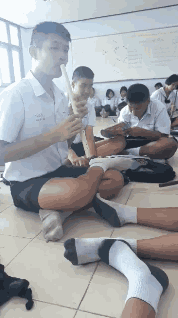 a boy sitting on the floor playing a flute with a shirt that says n.o.s.s. on it
