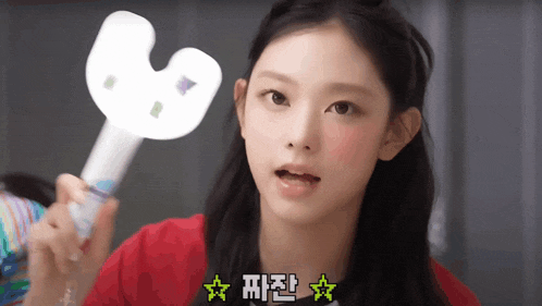 a girl in a red shirt is holding a light stick with chinese writing on it ..