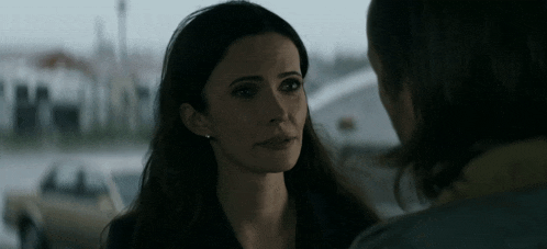 a man and a woman are looking at each other in a parking lot .