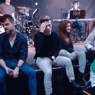 a group of people are sitting on a bench in front of a stage .