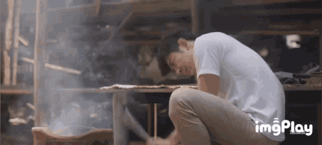 a man in a white shirt is kneeling down with his head down