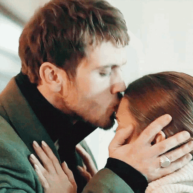 a man is kissing a woman on the forehead while wearing a ring