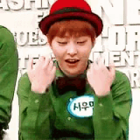 a man wearing a red hat and a green shirt is making a fist gesture .
