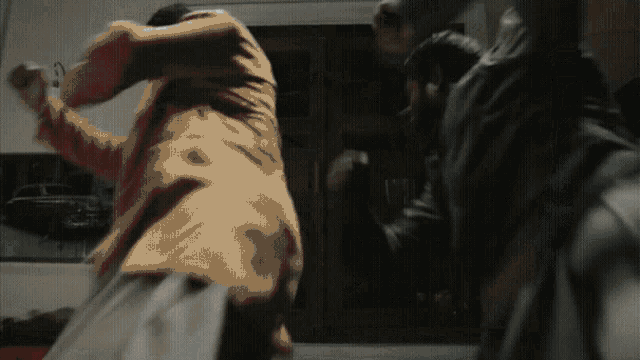 a man in a brown jacket is fighting another man