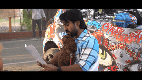 a man holding a dog while looking at a piece of paper