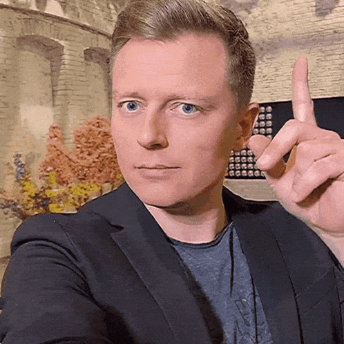 a man in a suit and a blue shirt is pointing up