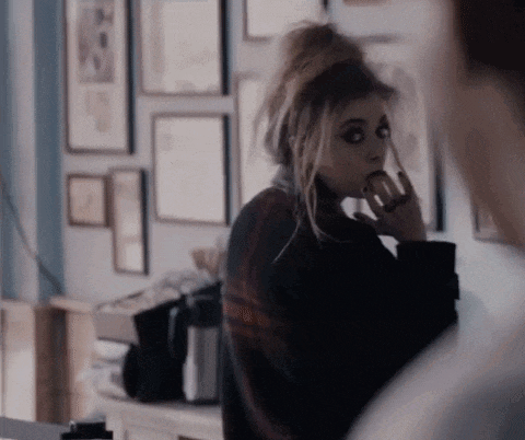 a woman in a plaid sweater is eating an apple and looking at a man .