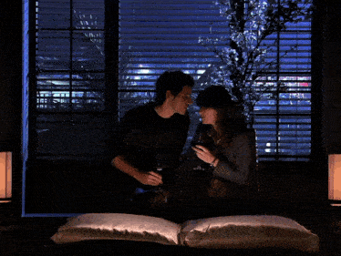 a man and woman are kissing in front of a window