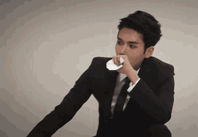 a man in a suit and tie wipes his nose