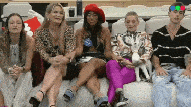 a group of people are sitting on a couch with one woman holding a dog .