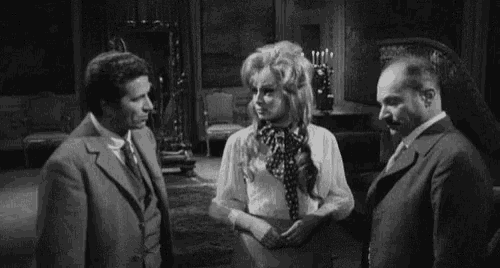 a black and white photo of a woman screaming while standing next to two men in a room .
