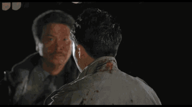 a man with blood on his face stands next to another man