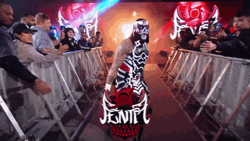 a wrestler in a mask is walking through a crowd with a sign that says jentel on it