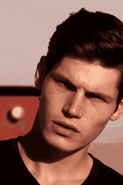 a close up of a young man 's face with a red object in the background