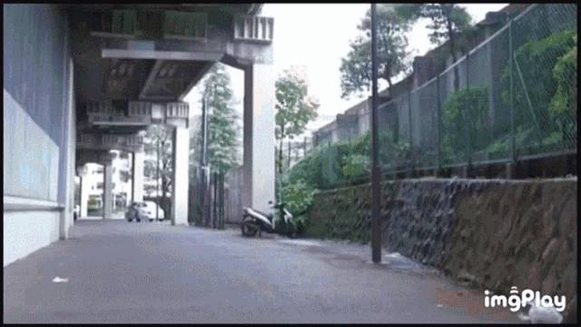 a motorcycle is parked on the side of a road under a bridge with imgplay written below it