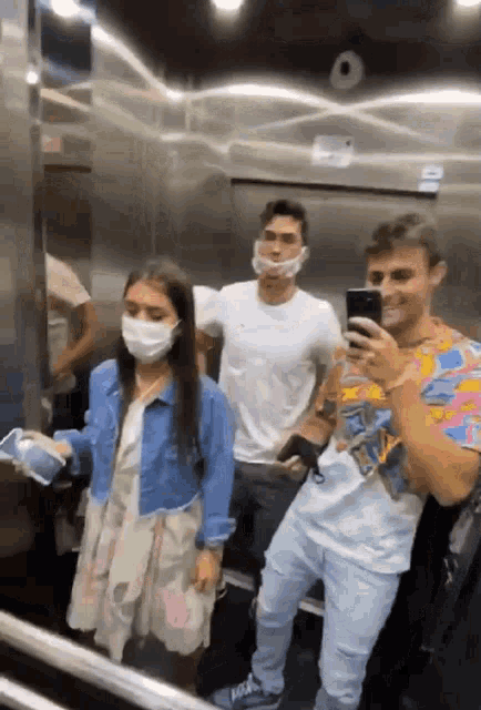 a group of people wearing face masks are standing in an elevator