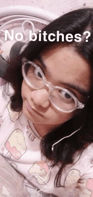a girl wearing glasses and headphones is taking a selfie while laying on a bed .