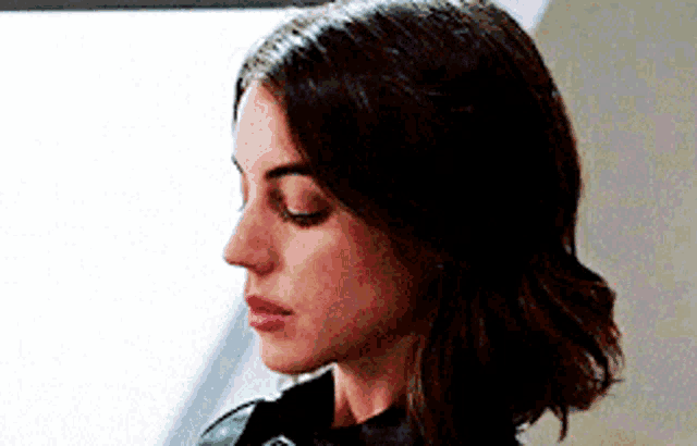 a close up of a woman 's face with her eyes closed and a black jacket .