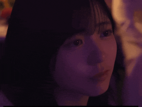 a close up of a woman 's face with purple light behind her