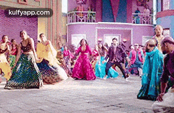 a group of people are dancing in front of a building in a crowd .